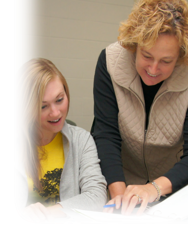 Teacher reviewing student's paper with student seated